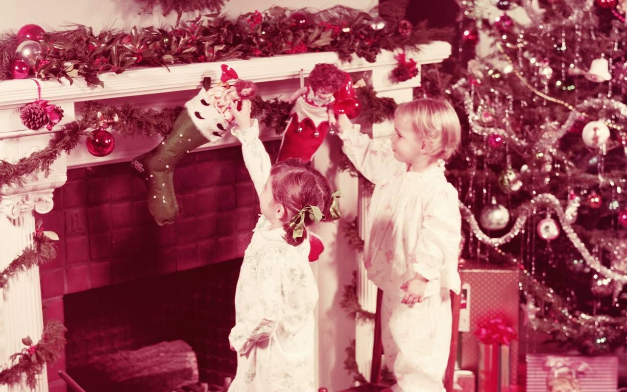 A vintage photo of two children looking at toys in their stockings. Next Avenue, christmas memories, childhood
