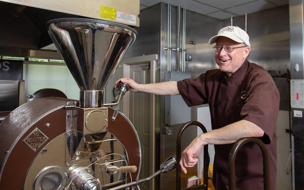 man smiling while working in a chocolate factory. Next Avenue