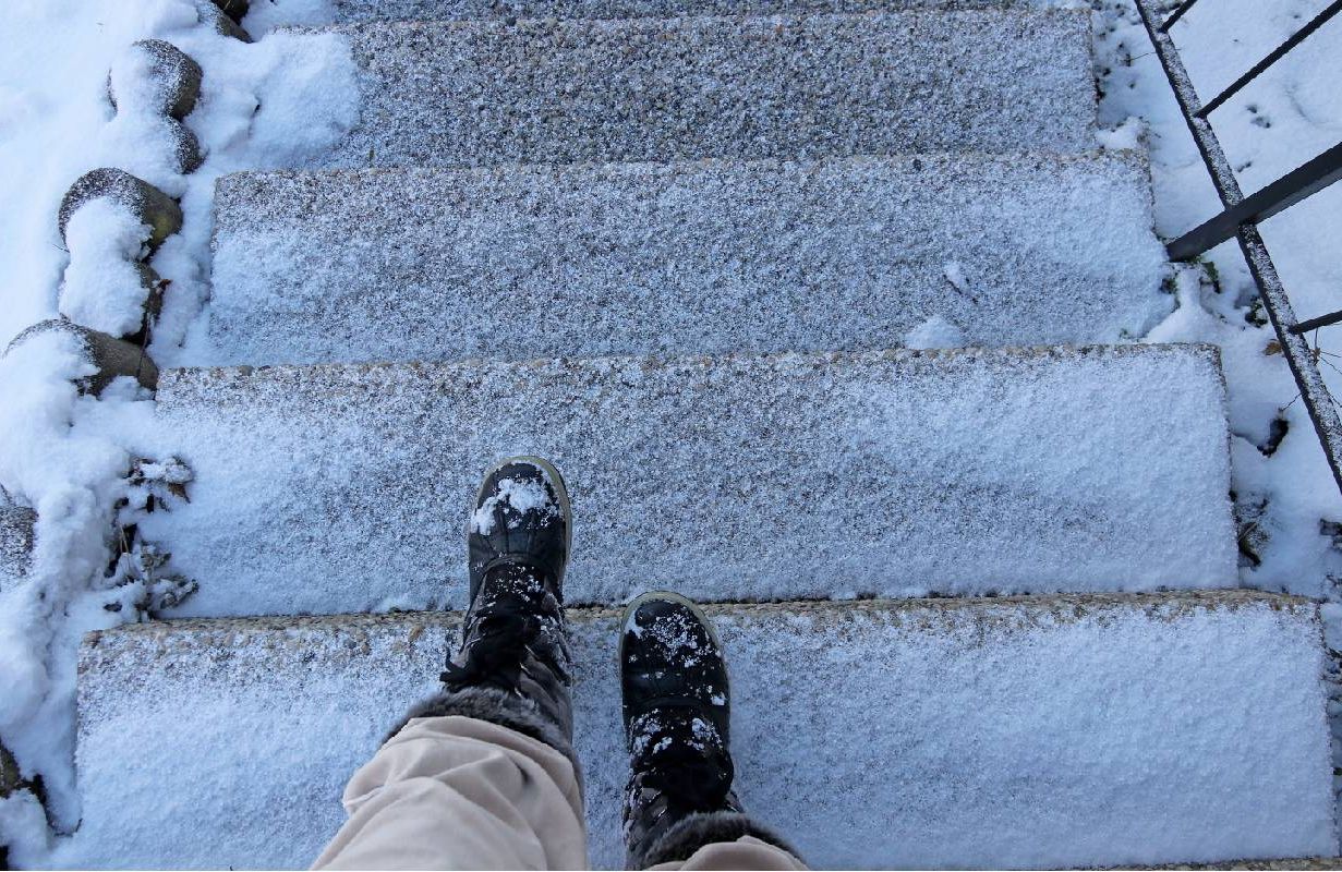 Looking down at steps with slippery ice and the feet of a person with fear of falling. Next Avenue