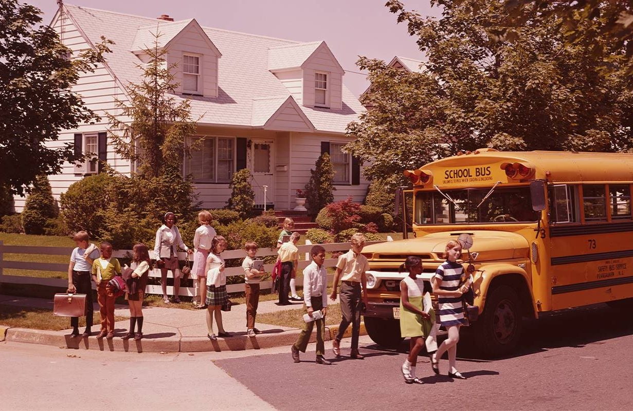 An old photo of kids getting off the school bus. Next Avenue