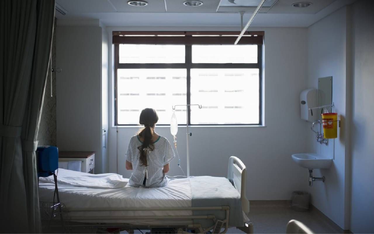 Rear view of a woman sitting up in a hospital bed. Next Avenue, ovarian cancer, treatment