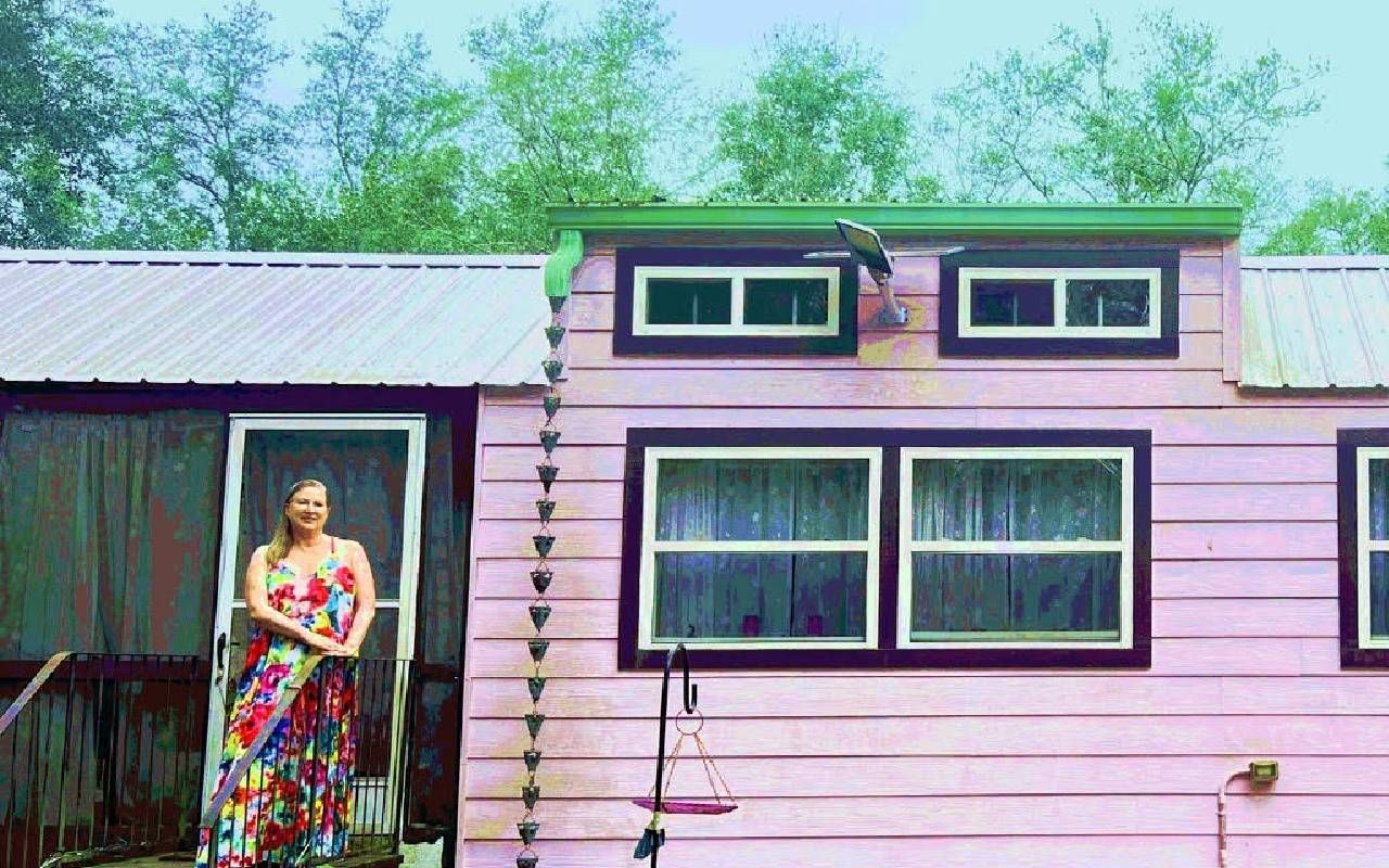 A woman standing outside of a pink house. Next Avenue, living on social security