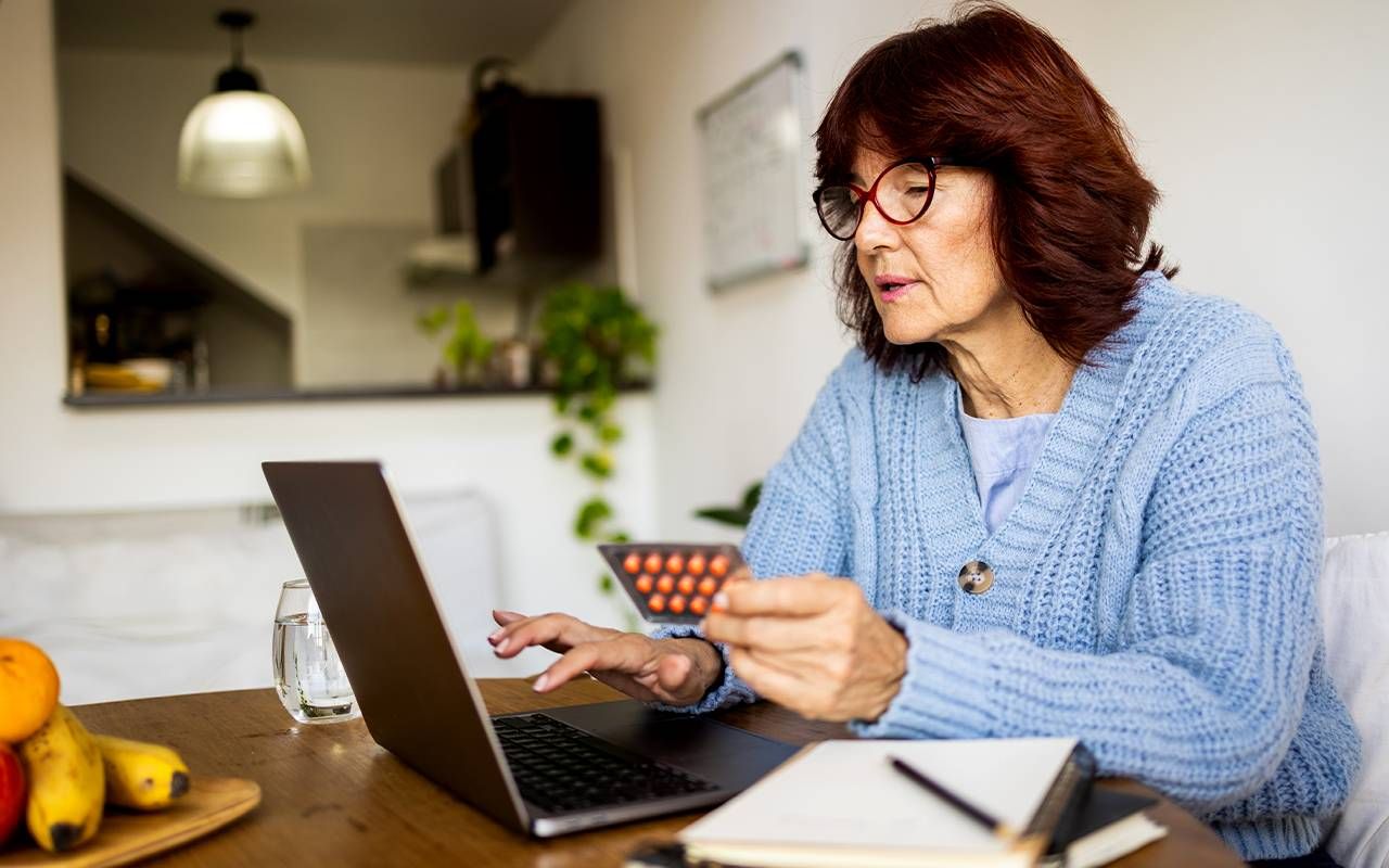 A woman on her laptop figuring out if her medication is covered by medicare. Next Avenue