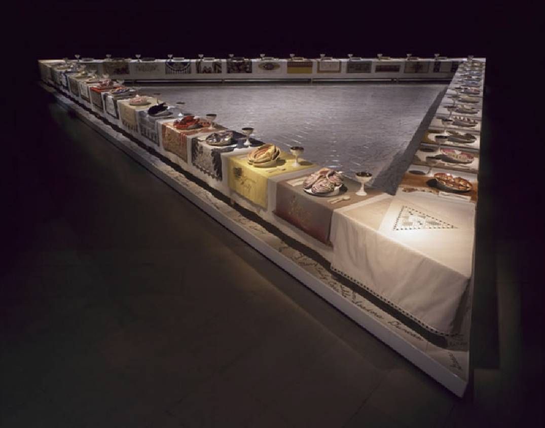 A dinner table shaped like a triangle with place settings. Next Avenue, Judy chicago