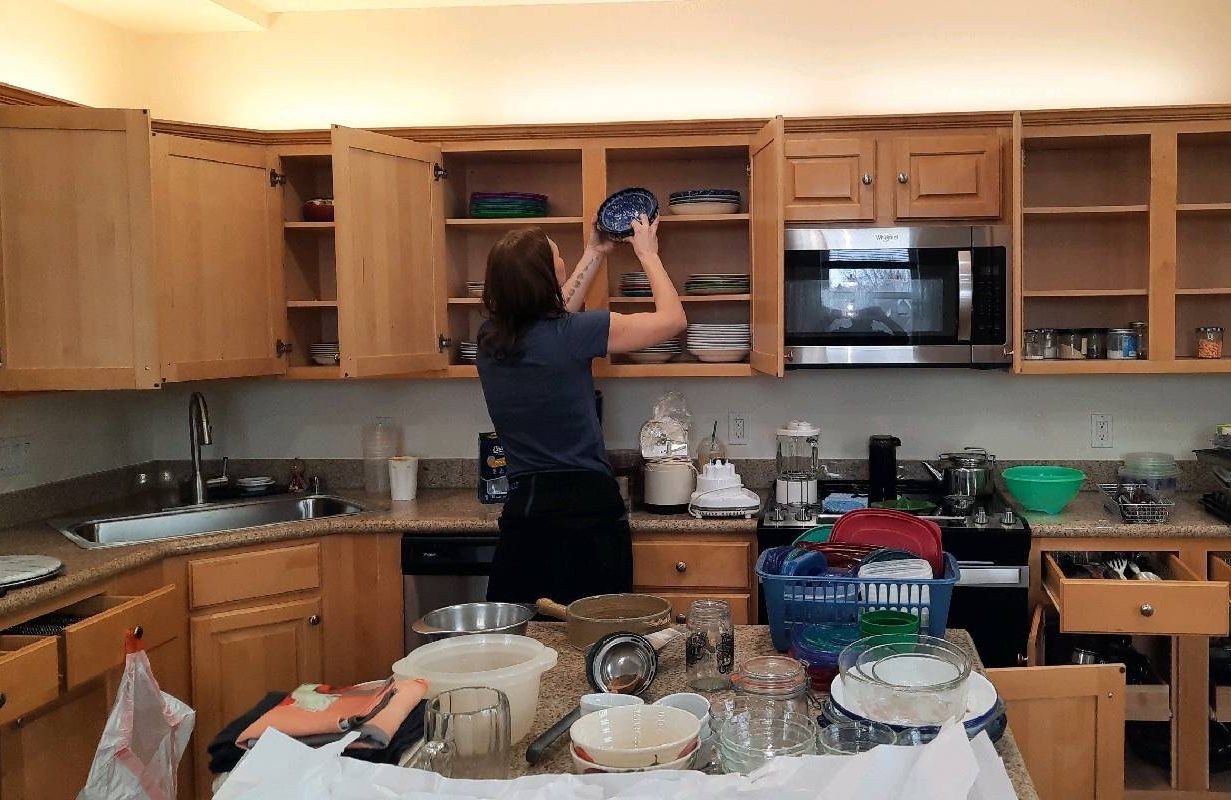 A person organizing dishes when downsizing. Next Avenue, bereavement cleanout service