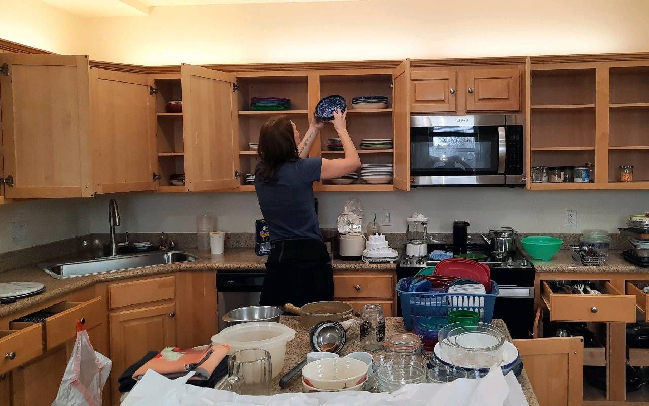 A person organizing dishes when downsizing. Next Avenue, bereavement cleanout service