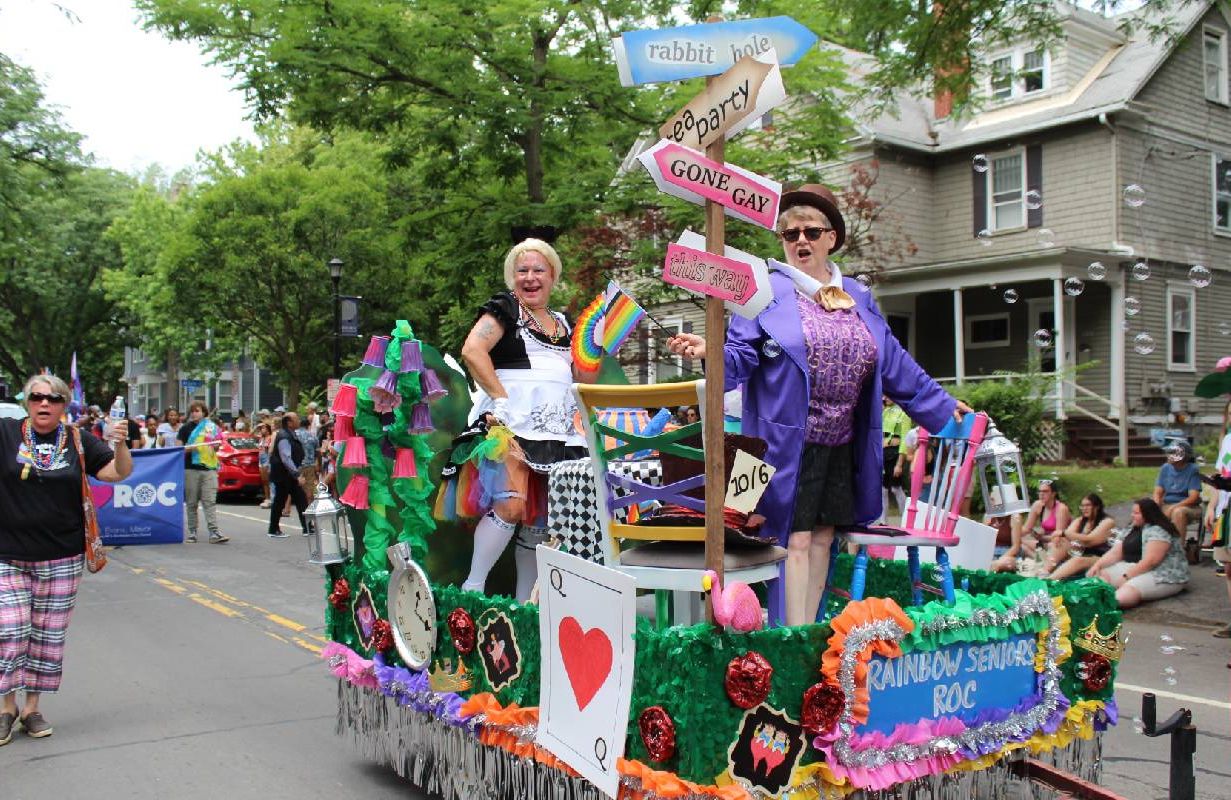 Two people standing on top of a float in a parade. Next Avenue, rainbow seniors, LGBTQIA older adults