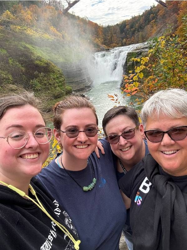 A group of people smiling in front of a waterfall. Next Avenue, rainbow seniors, LGBTQIA older adults
