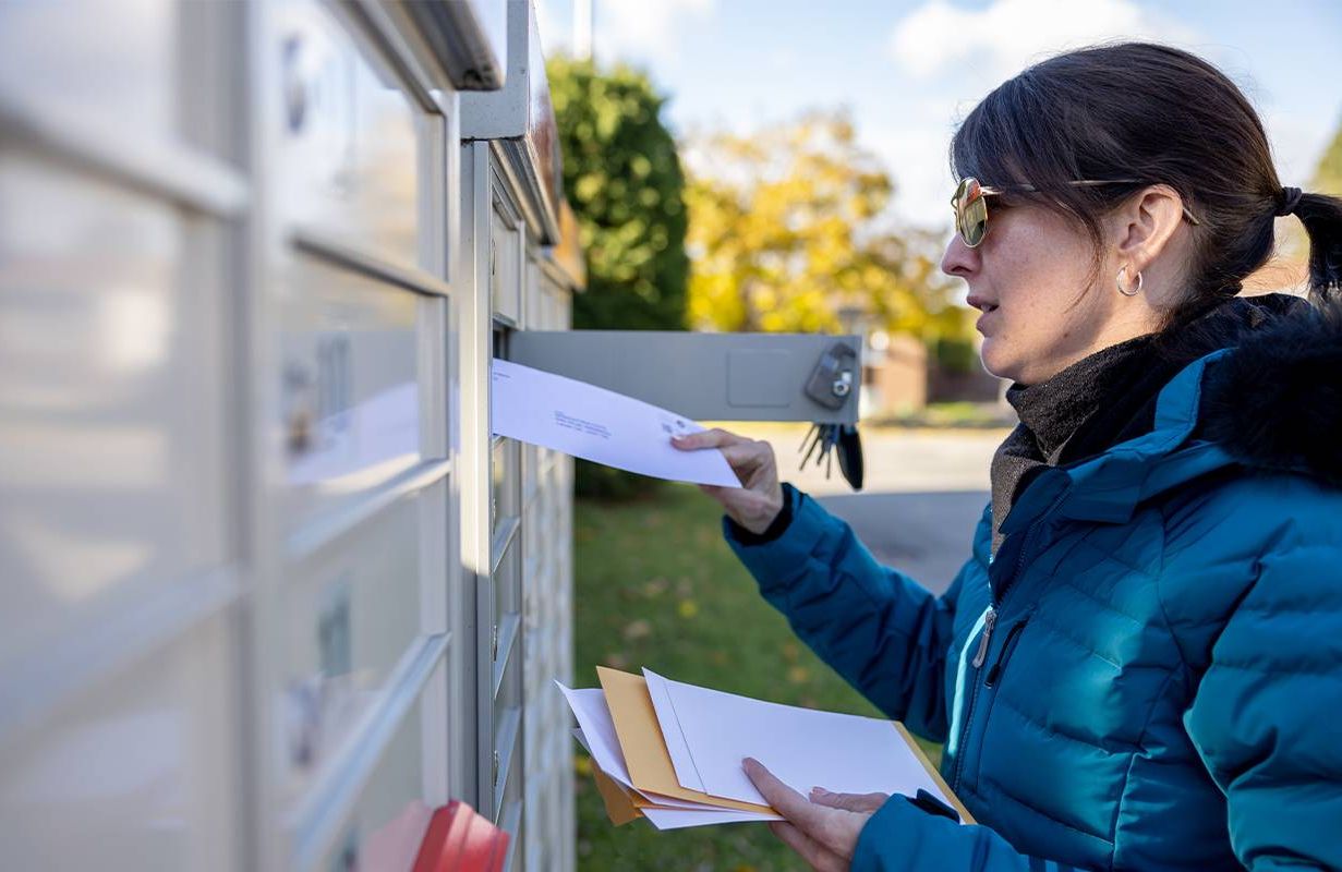 A woman putting mail in her mailbox. Next Avenue, check washing fraud