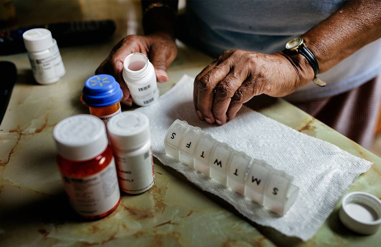 A woman using a pill box to organize and safely manage her medication. Next Avenue