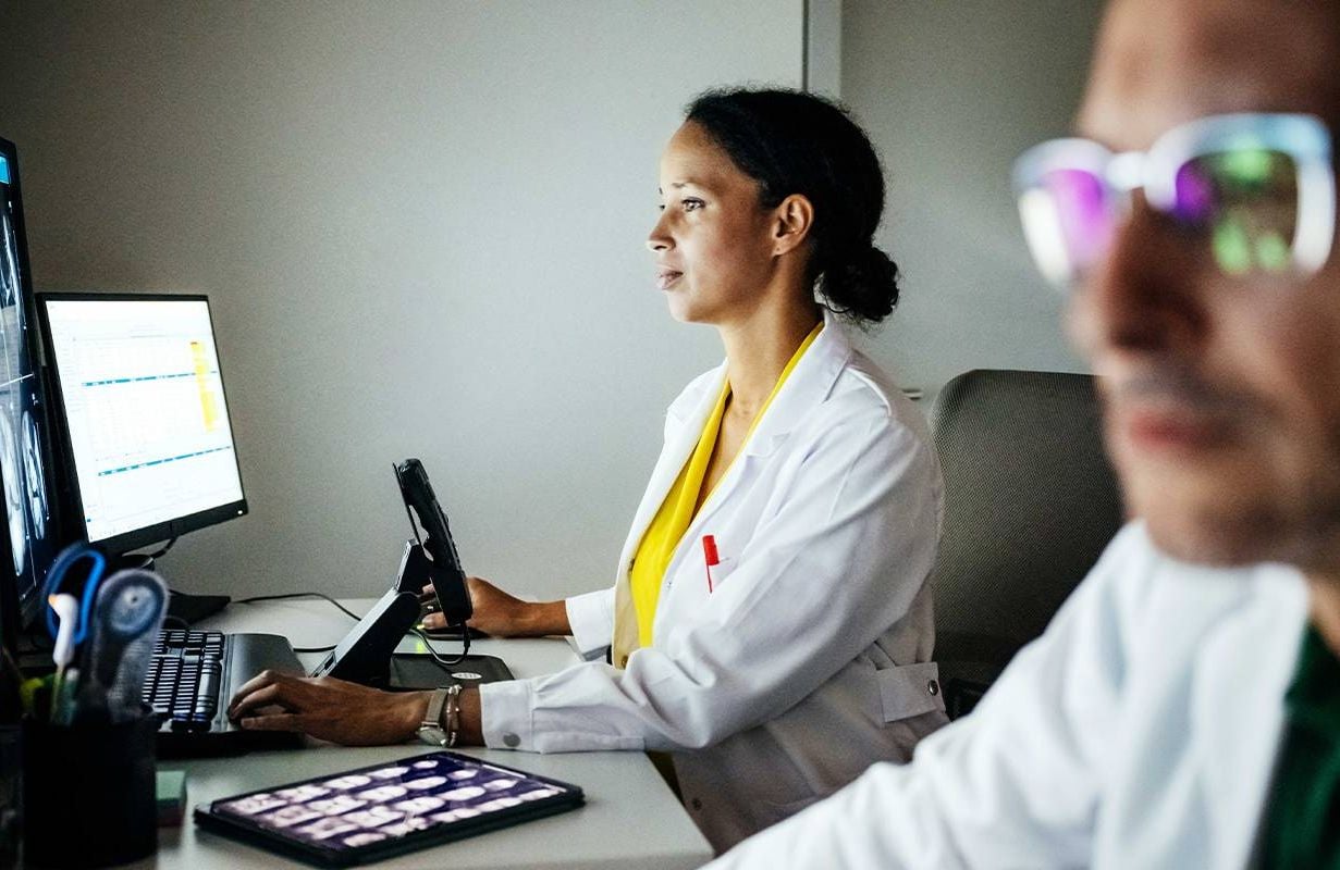 Two doctors using computers to communicate in patient medical portals. Next Avenue, patient portal fees