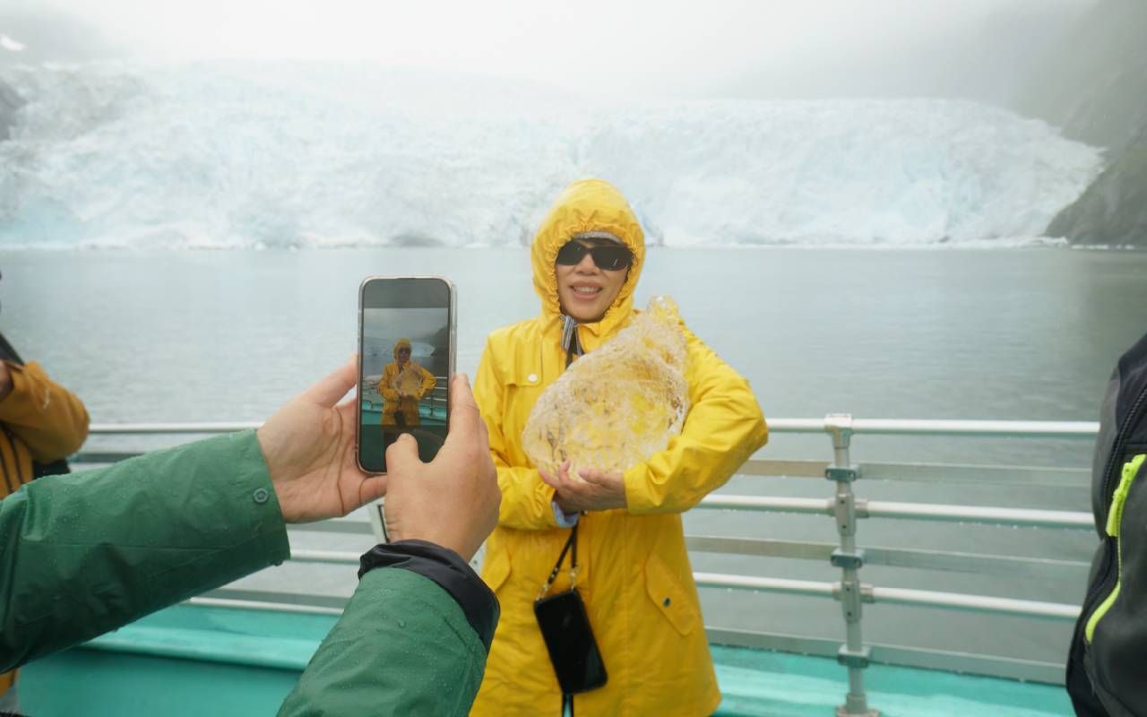 A person posing with a chunk of glacier ice. Next Avenue, reverse snowbird