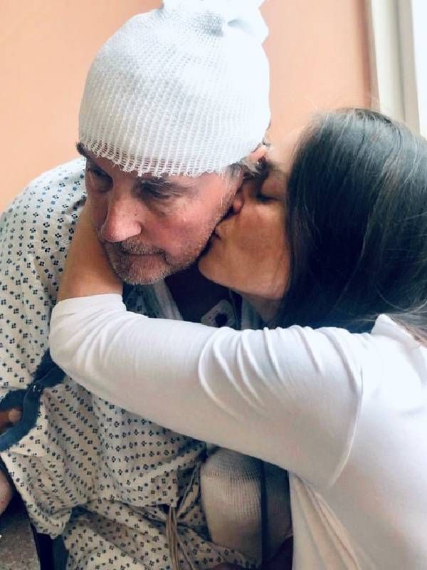 A man wearing gauze on his head being hugged by his wife. Next Avenue, terminal cancer, Rod Nordland