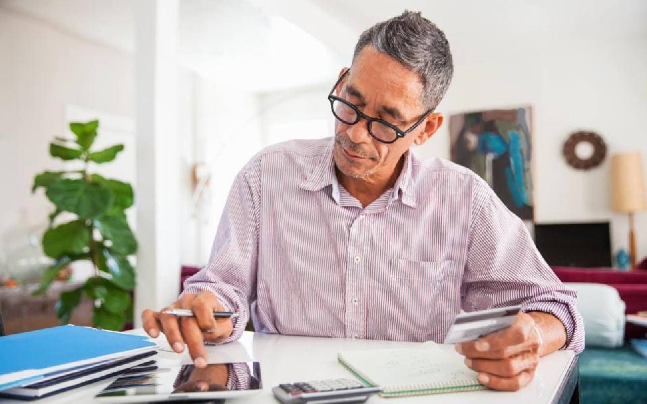 An older man paying a credit card bill to boost his credit. Next Avenue