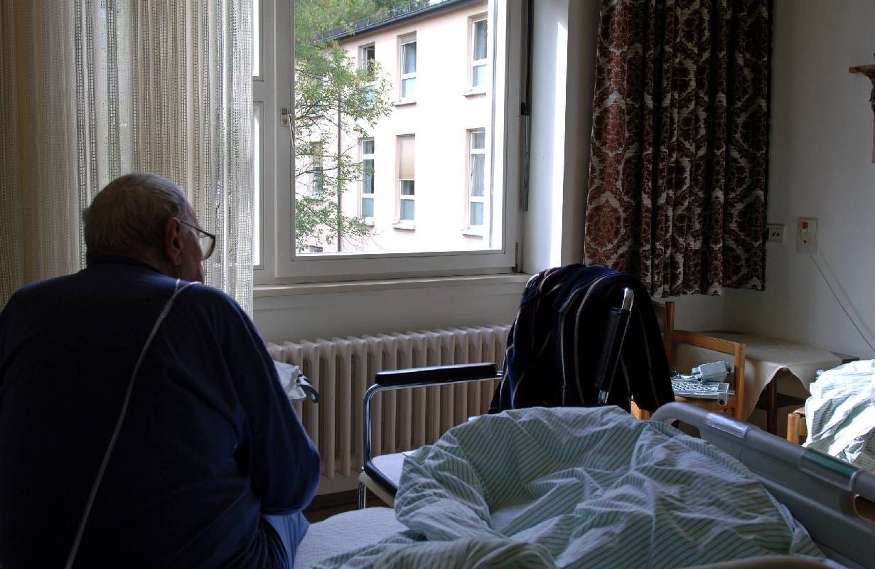 An older man sitting on a bed in a nursing home. Next Avenue, elder abuse, assisted living