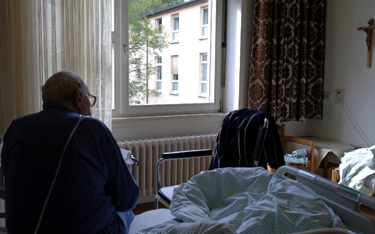 An older man sitting on a bed in a nursing home. Next Avenue, elder abuse, assisted living