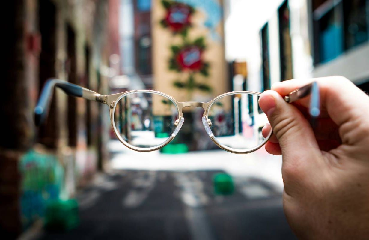 A person holding up their pair of glasses. Next Avenue