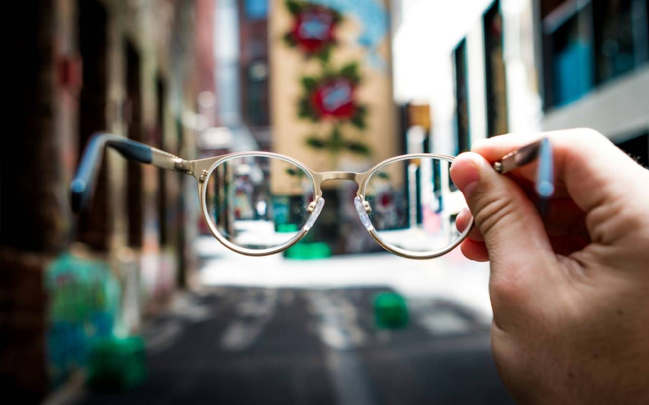 A person holding up their pair of glasses. Next Avenue