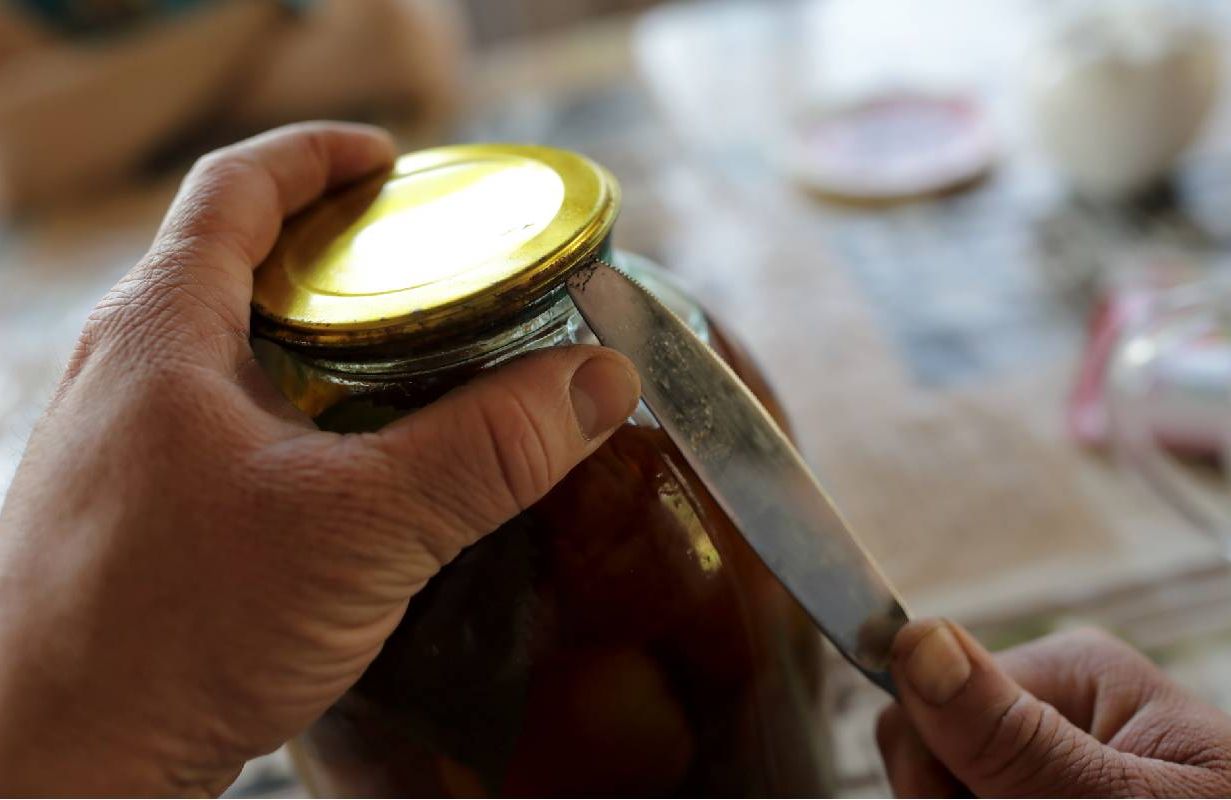 A person struggling to open a jar of pickles. Next Avenue, grip strength, health