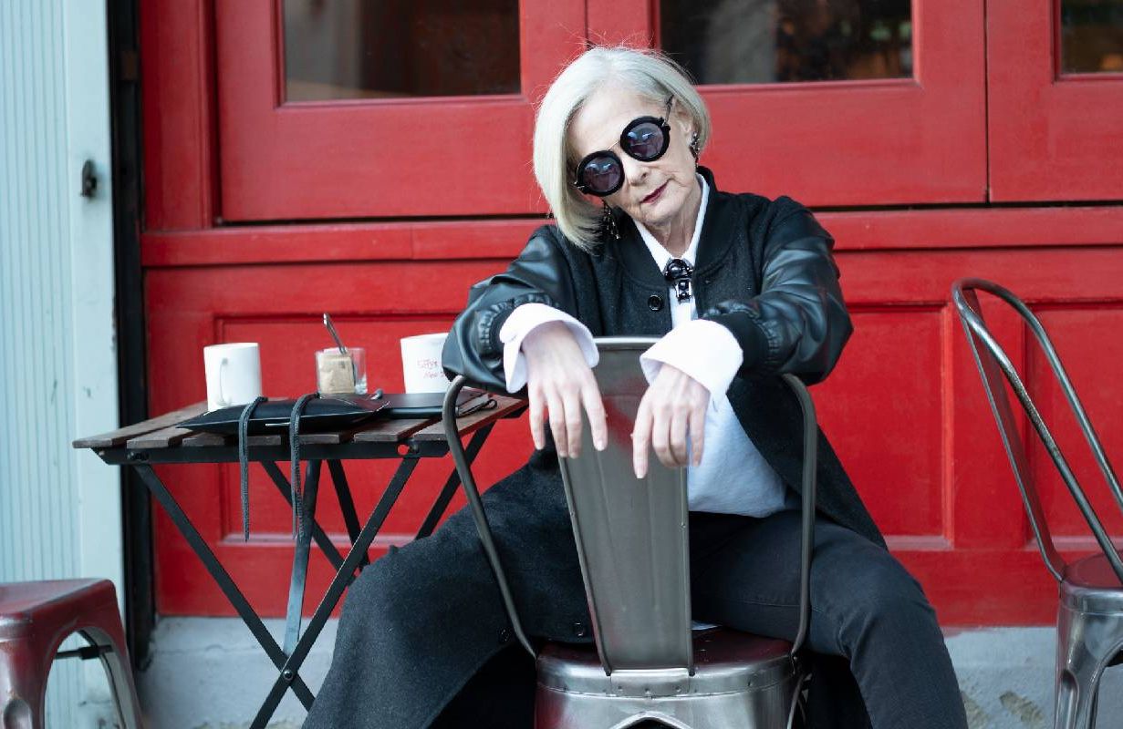 A fashionable older woman posing outside of a cafe. Next Avenue, Lyn Slater
