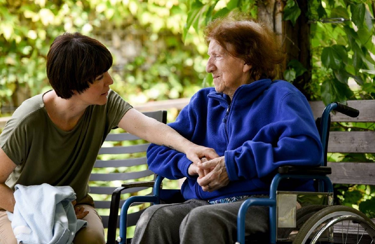 A family caregiver helping her loved one while sitting outside. Next Avenue, caregivers