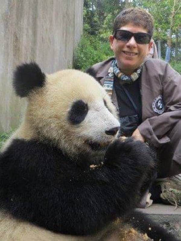 A woman sitting next to a giant panda. Next Avenue, wildlife conservation, travel