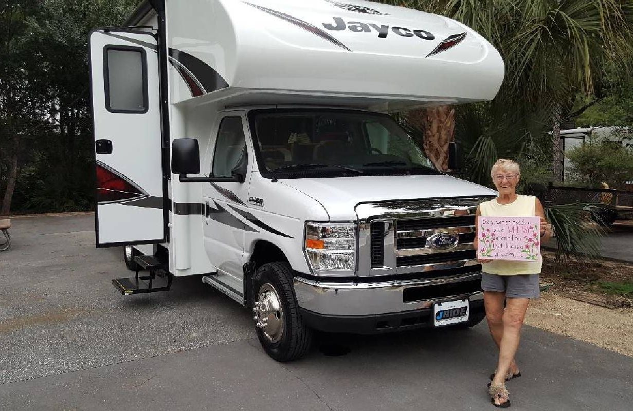 A woman smiling and standing in front of her RV. Next Avenue, RV