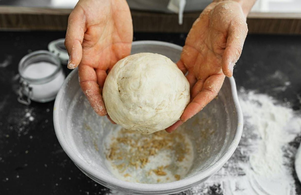 A close up shot of someone holding dough while doing a baking school from home. Next Avenue