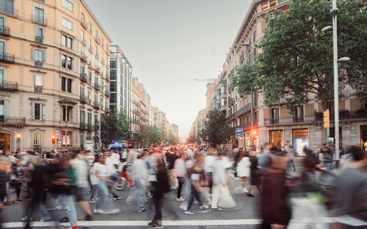 A blurry crowd of people walking through a crosswalk. Next Avenue ,busyness culture