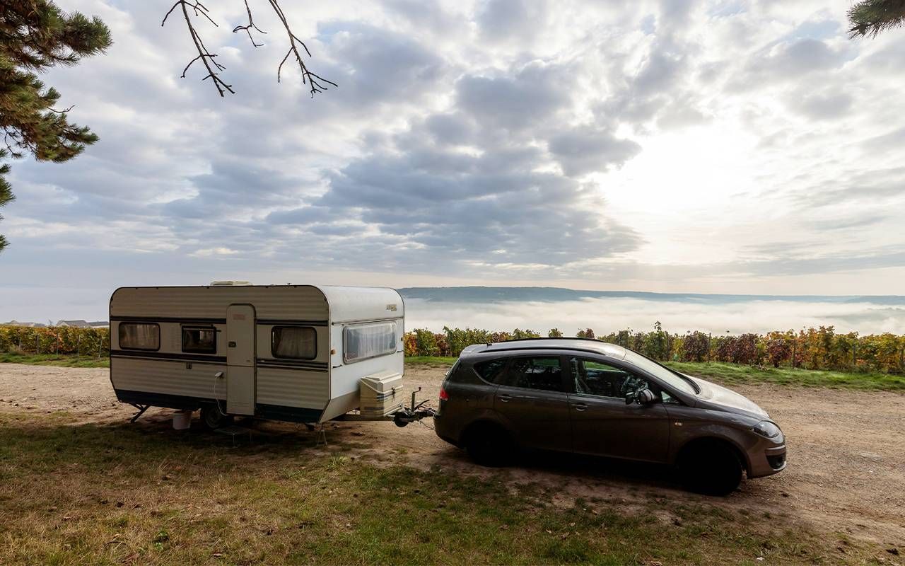 A car with an RV trailer parked at a campsite. Next Avenue, summer travel, carbon footprint
