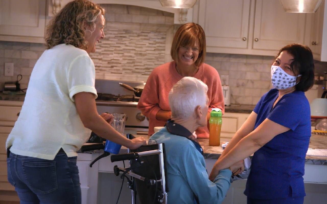 Caregivers helping an older man inside a home. Next Avenue, Wine, Women and Dementia, caregivers