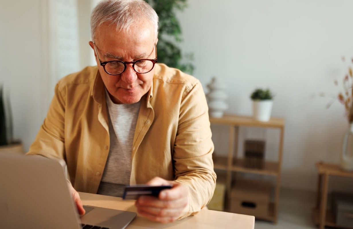A scam victim typing his credit card info into his computer. Next Avenue,