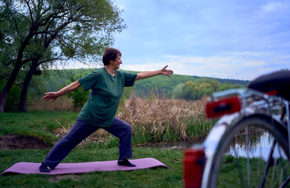 A woman with osteoporosis practicing yoga outside. Next Avenue