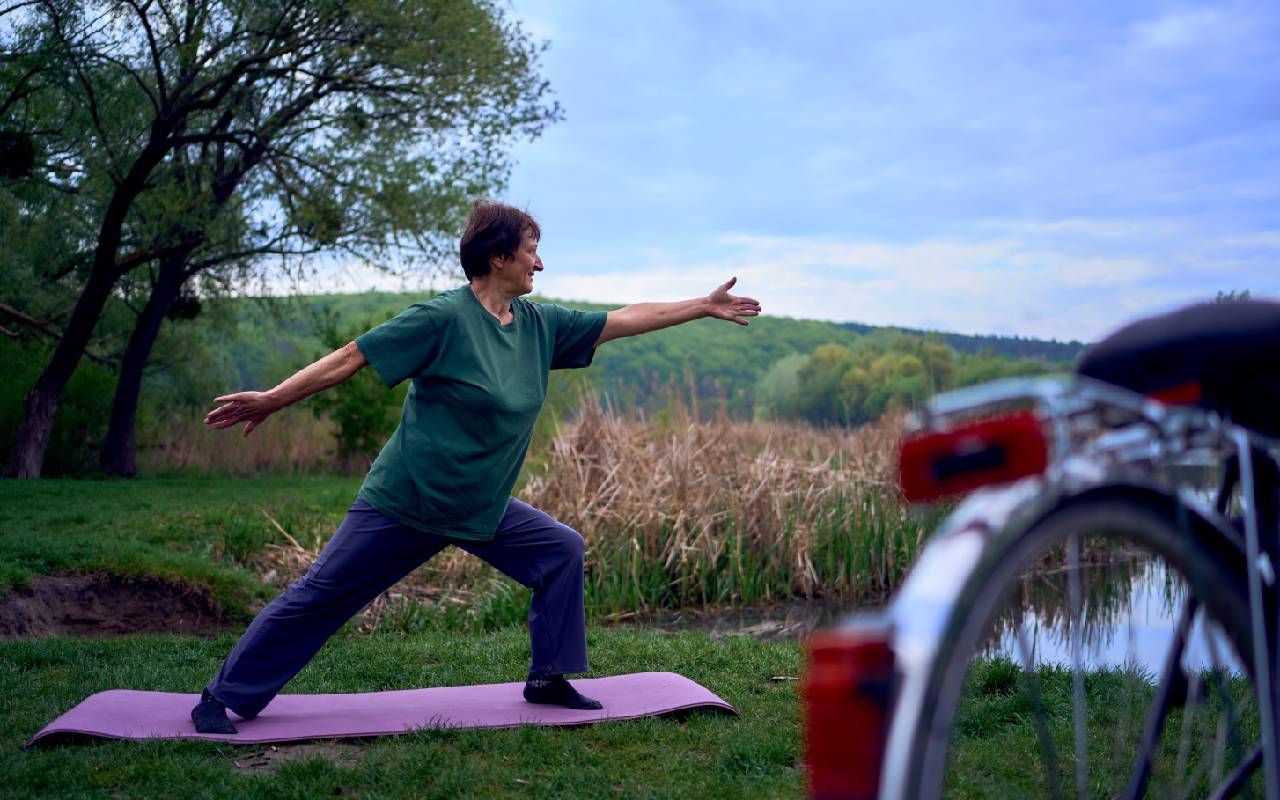 A woman with osteoporosis practicing yoga outside. Next Avenue