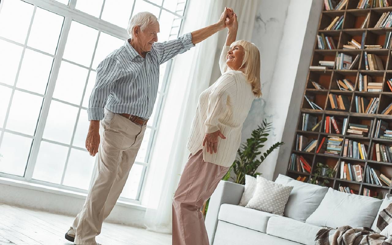 Two older adults dancing together at home. Next Avenue