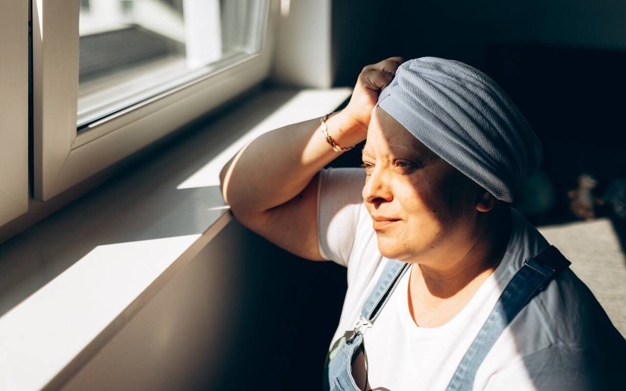 A woman with a chronic condition looking out of a window. Next Avenue, overlap of chronic pain and anxiety and depression