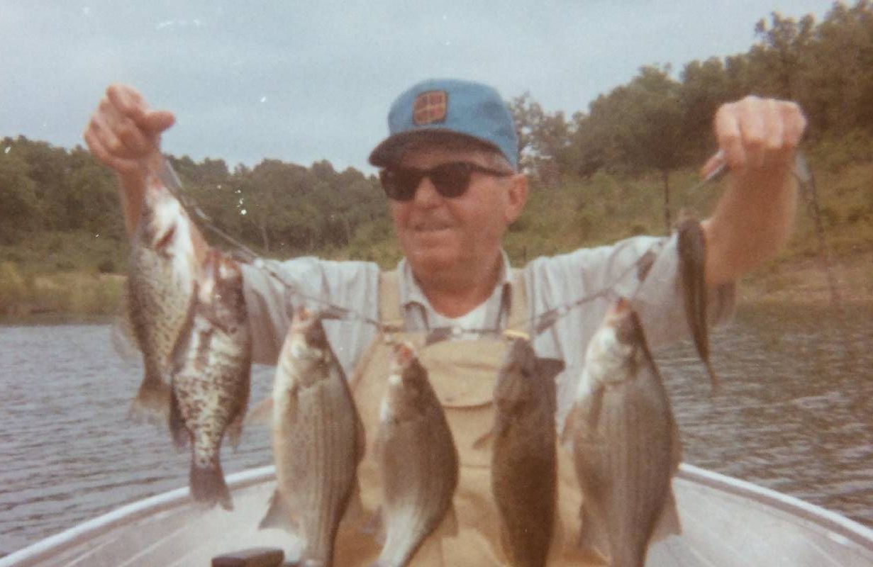 A photo of a man holding up freshly caught fish. Next Avenue, greatest generation dad