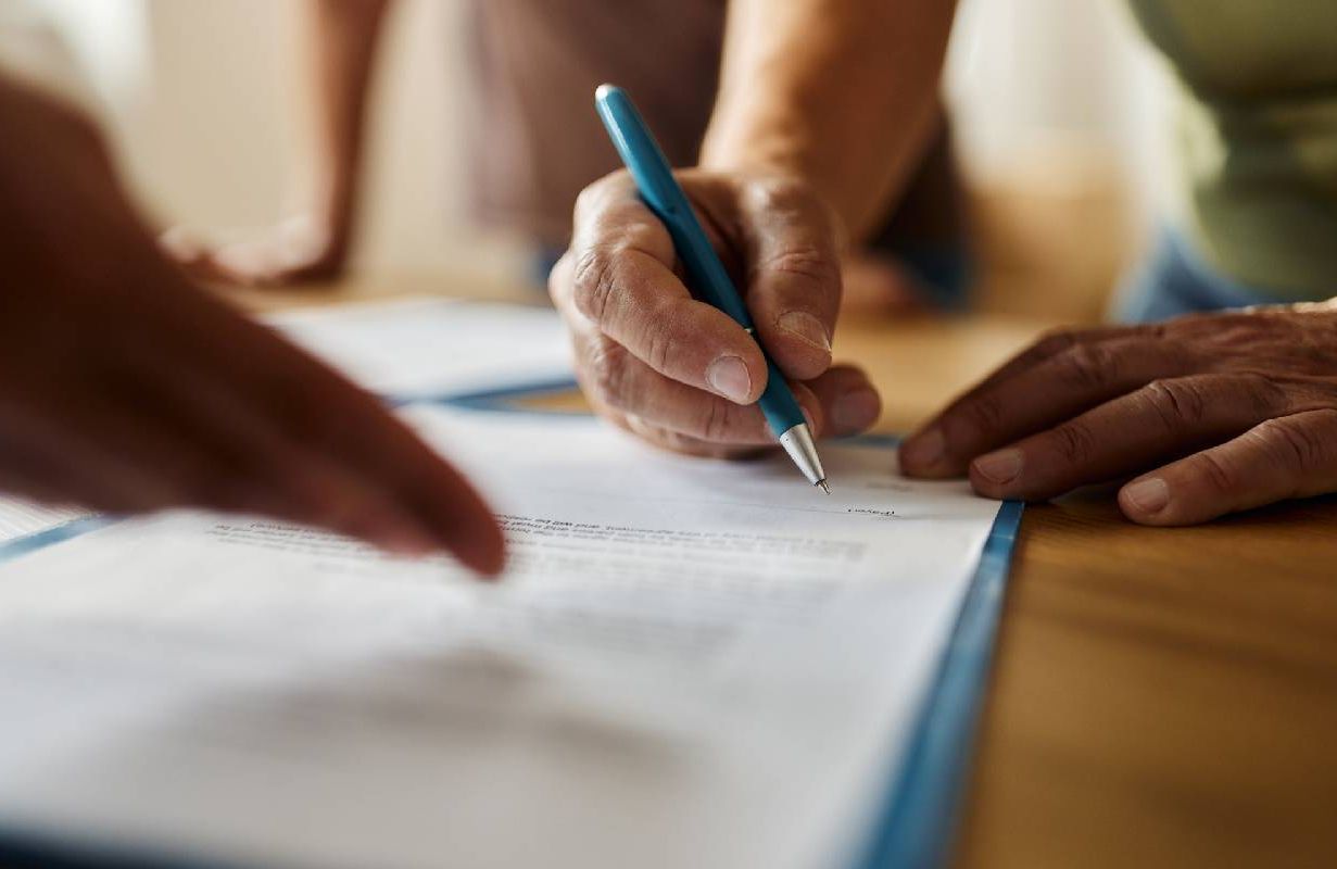 A person signing paperwork for a reverse mortgage. Next Avenue