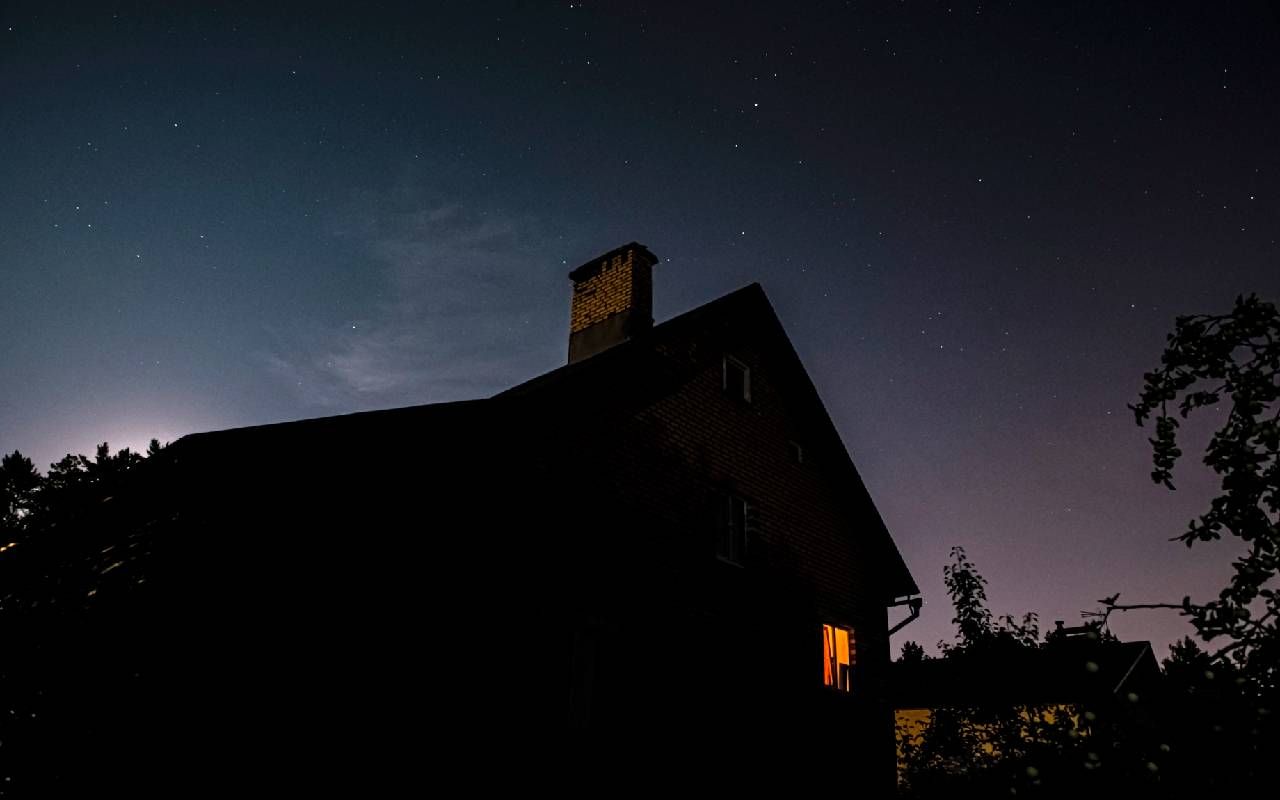 The silhouette of a house with a light on and the night sky. Next Avenue, sleeping pill alternatives