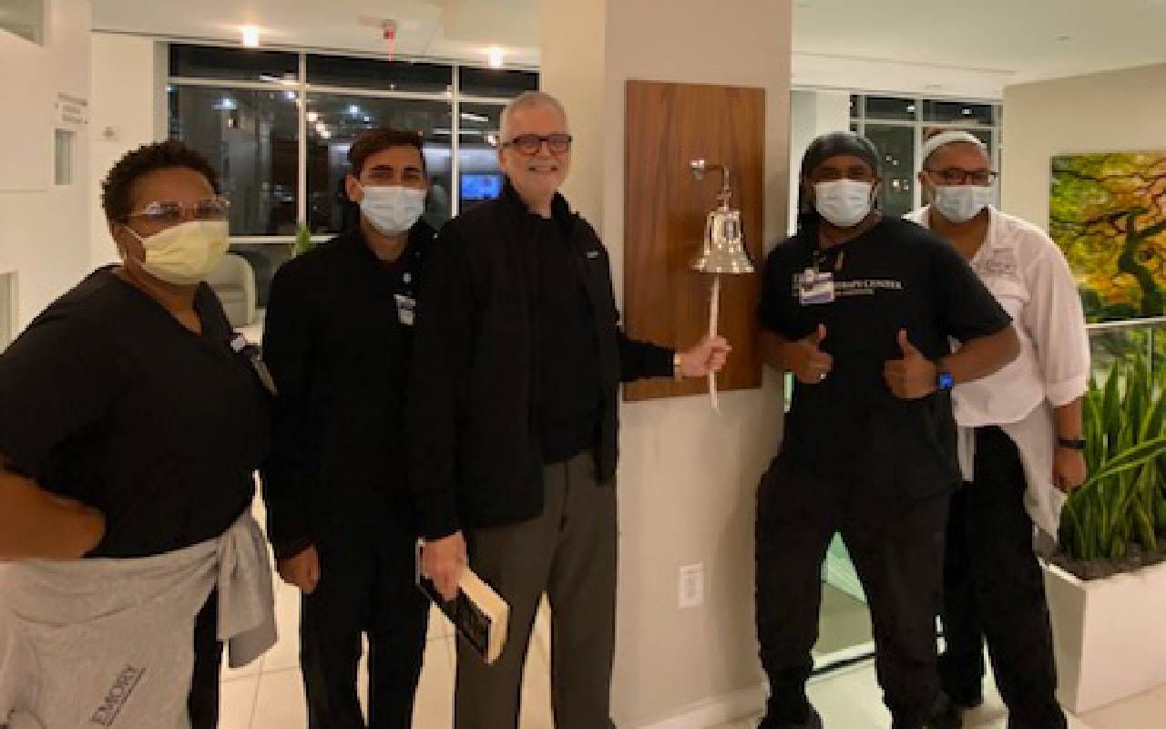 A man standing with several nurses and doctors ringing a bell in a hospital. Next Avenue, prostate cancer