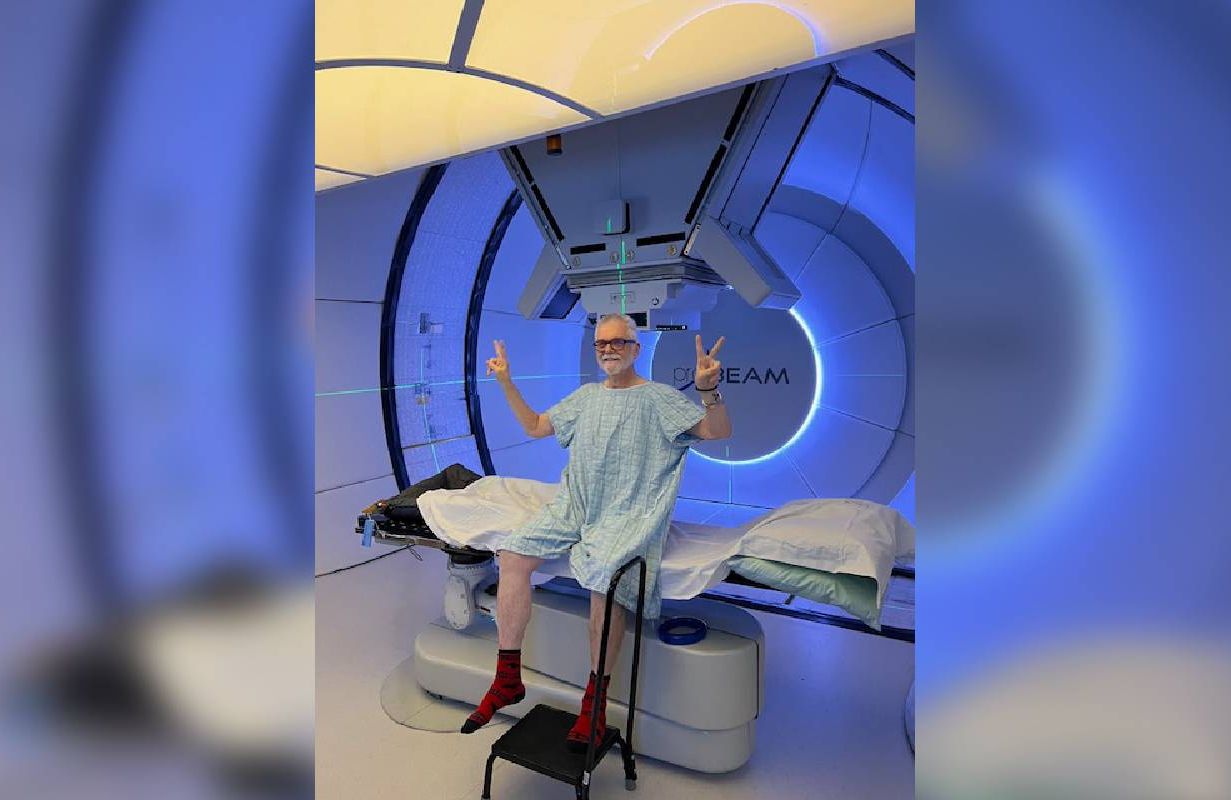 A man sitting up in front of a large proton therapy machine. Next Avenue, prostate cancer