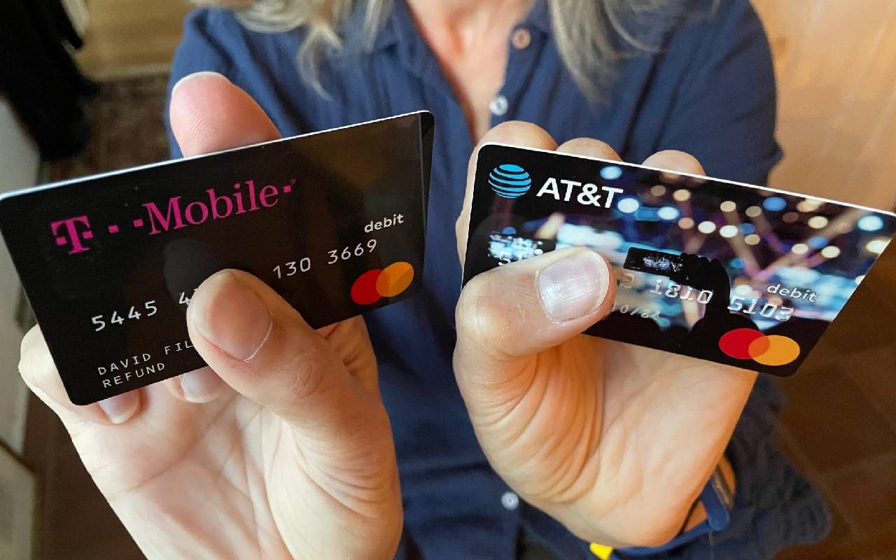 A person holding up two refund cards. Next Avenue