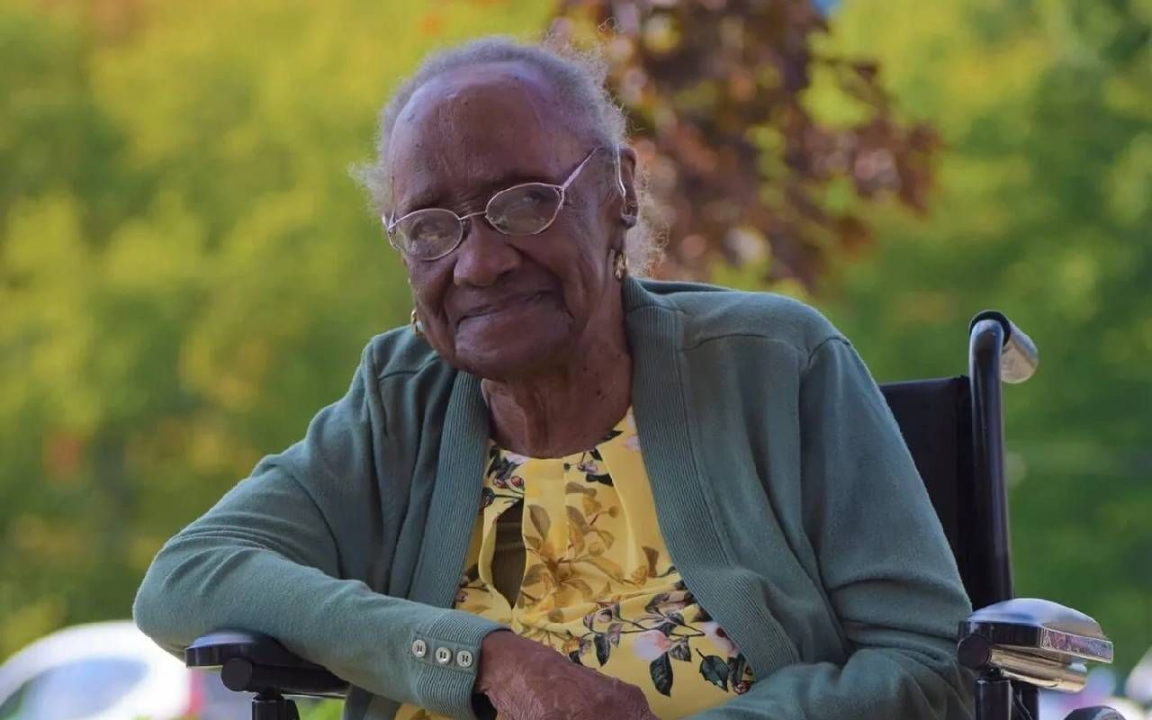 Headshot of a woman sitting outside and smiling. Next Avenue, living to 100