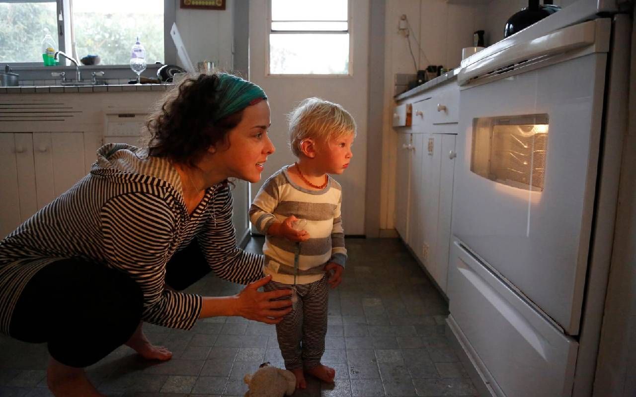 A parent looking in the oven with her child. Next Avenue, parentless parents