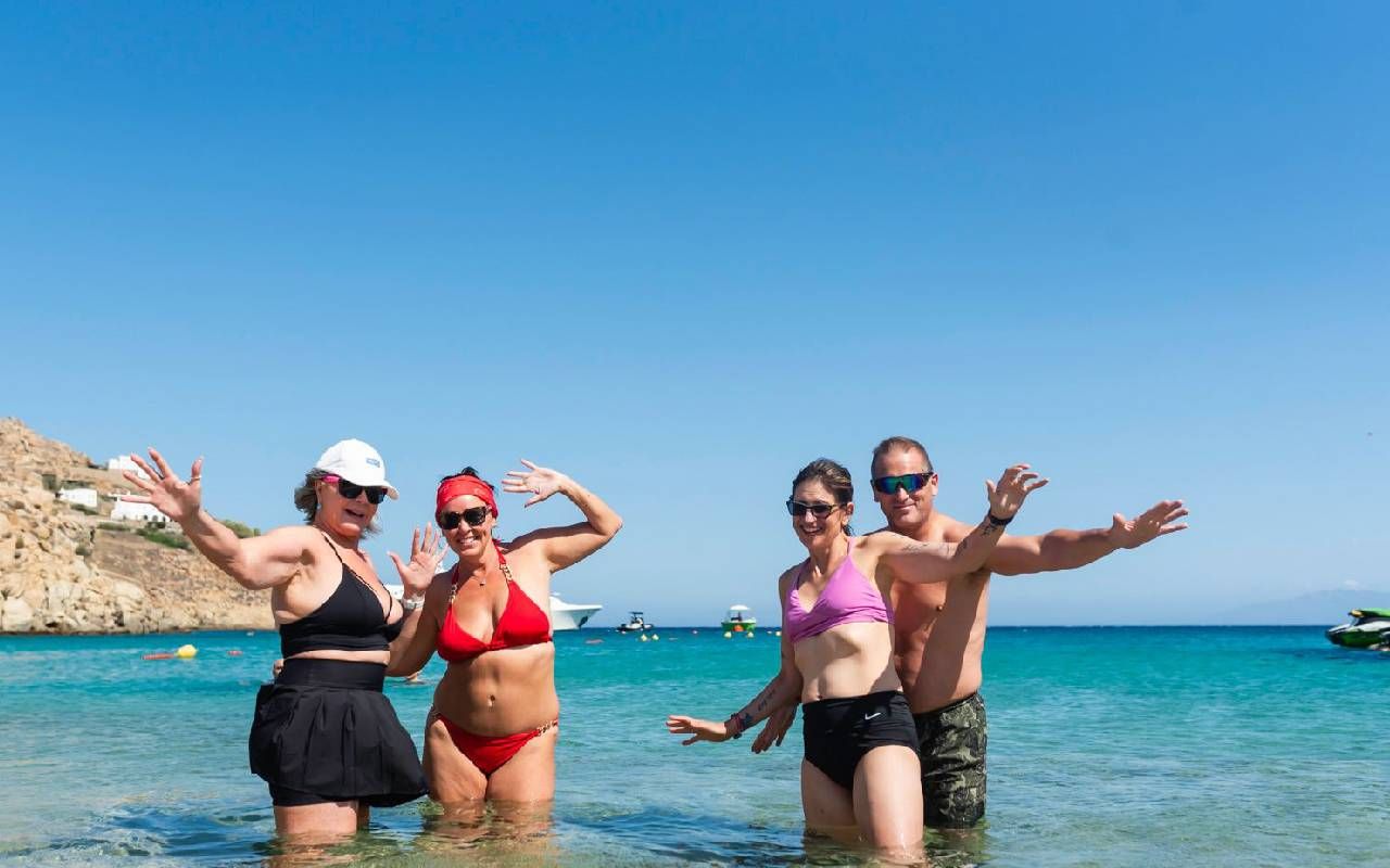 A group of people smiling in the ocean. Next Avenue, sober travel,