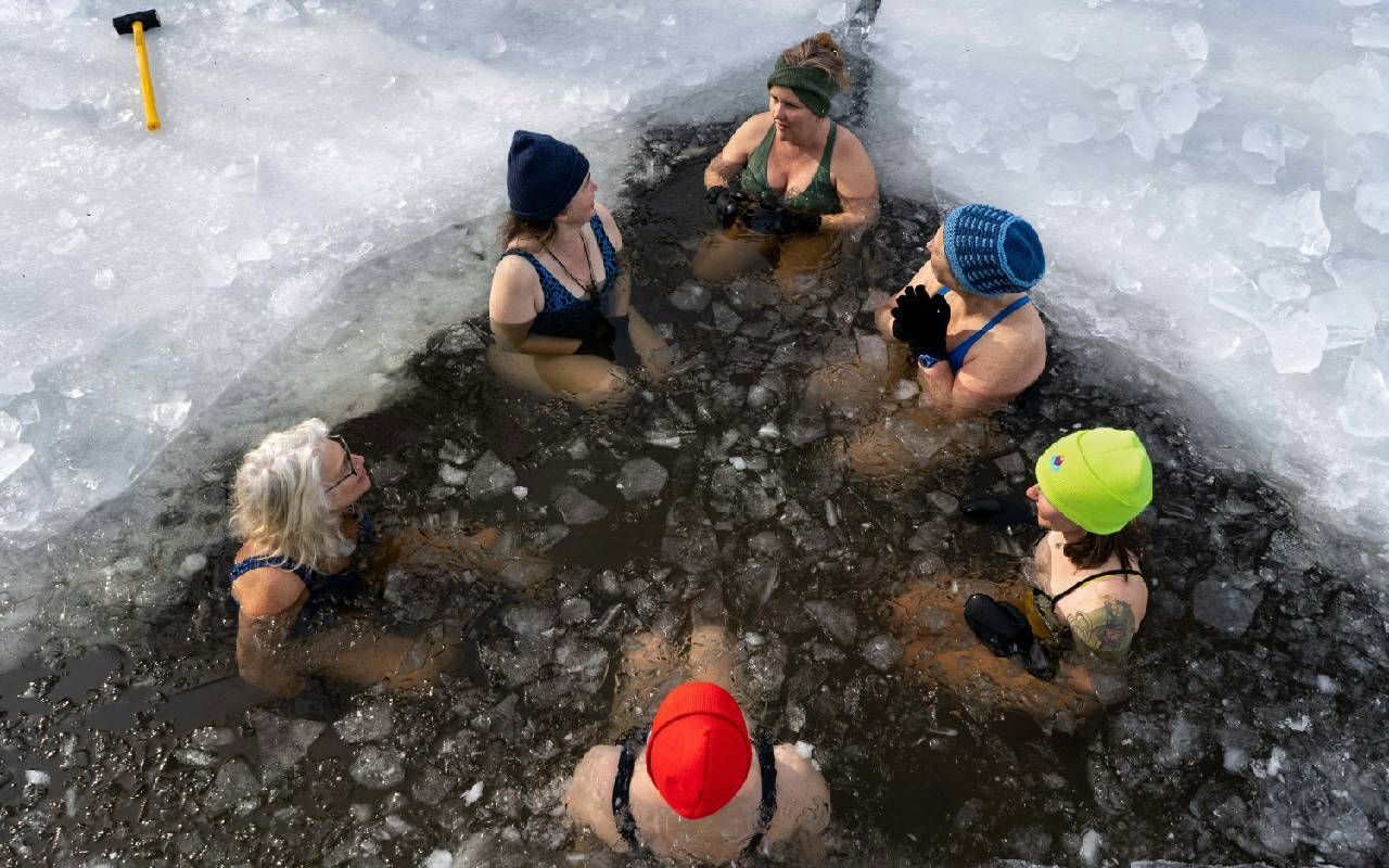 A group of people sitting in icy water. Next Avenue, cold plunge