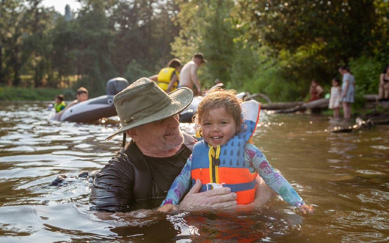 A grandfather swimming in a river with his grandchild. Next Avenue, grandparenting, mental health
