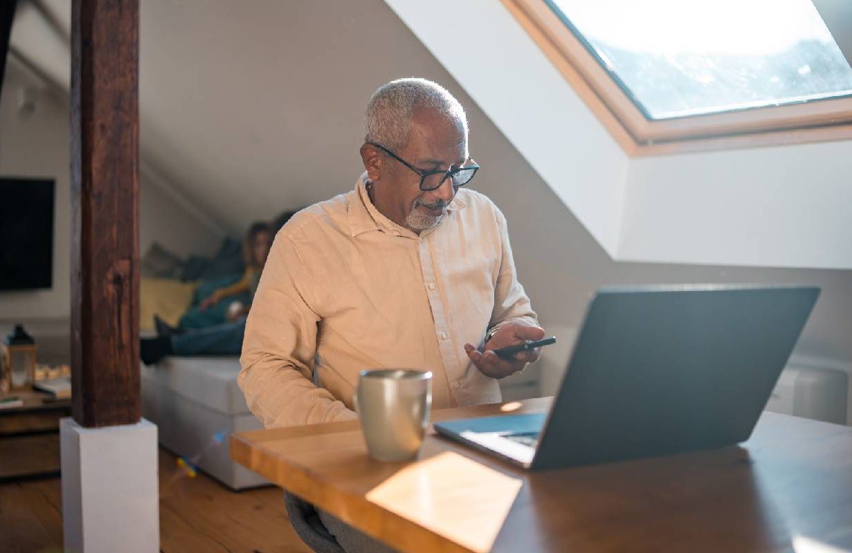 A retired person focused on work using a laptop at a home office setup. Next Avenue, retirement resume