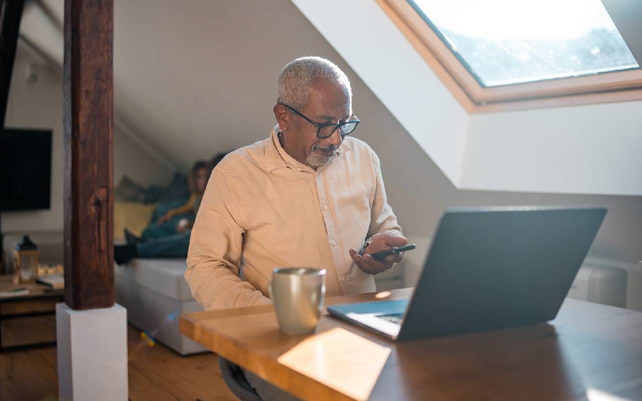 A retired person focused on work using a laptop at a home office setup. Next Avenue, retirement resume