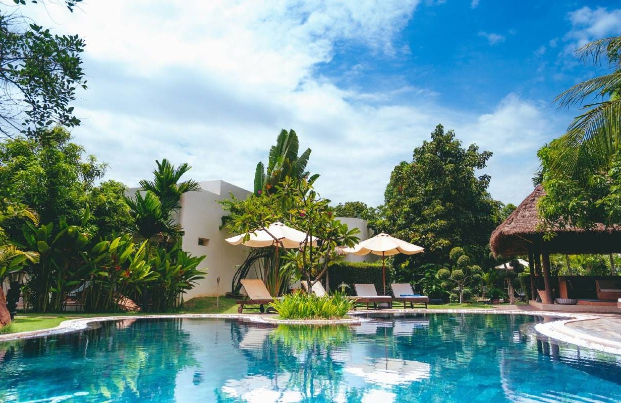 A hotel pool with sun umbrellas. Next Avenue, credit card perks, travel rewards